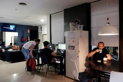 a group of people sitting at a table in a kitchen at Alternative Creative Youth Hostel Barcelona in Barcelona