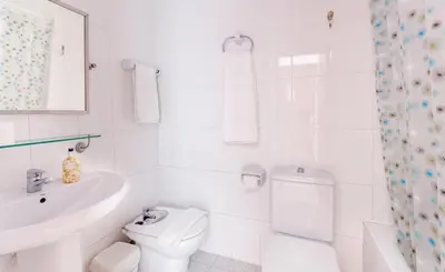 a white bathroom with a toilet and a sink at Hola Sitges Apartments in Sitges