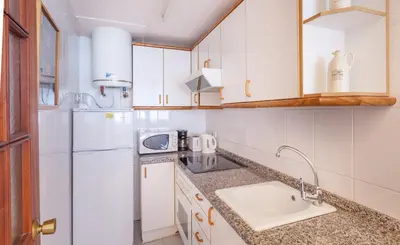 a kitchen with a sink and a white refrigerator at Hola Sitges Apartments in Sitges