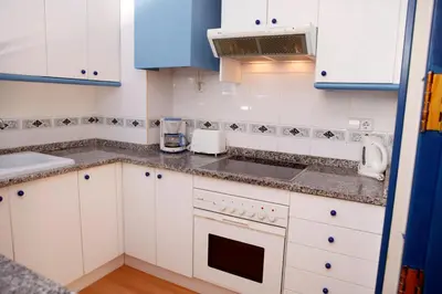 a kitchen with white cabinets and a sink at Hola Sitges Apartments in Sitges