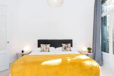 a bedroom with a large bed with a yellow blanket at Montaber Apartment - Trafalgar in Barcelona