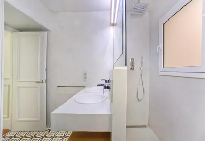 a white bathroom with a sink and a mirror at Montaber Apartment - Bailén in Barcelona