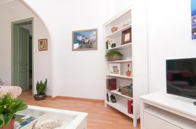 a living room with a tv and white shelves at Montaber Apartment - Sant Antoni in Barcelona