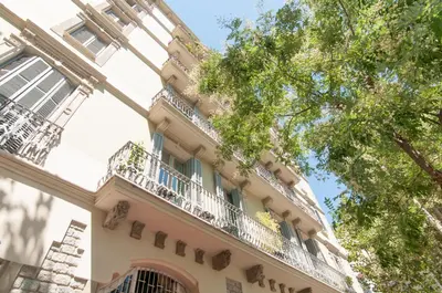 a building with a balcony and a tree at Montaber Apartment - Sant Antoni in Barcelona