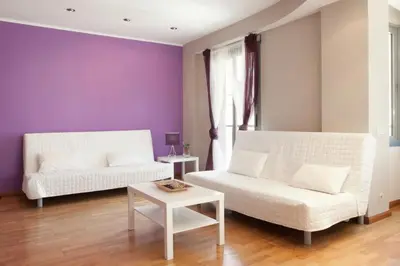 a living room with two white couches and a purple wall at Sagrada Familia Apartment 265 in Barcelona