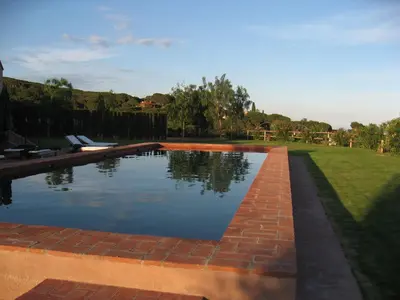 a swimming pool in a yard with a brick wall at Can Mora de Dalt in Sant Vicenç de Montalt