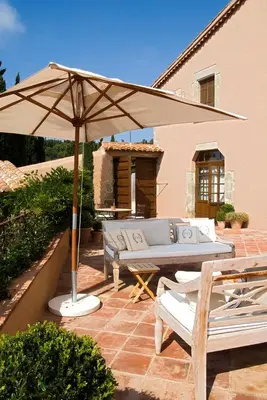 a patio with a couch and an umbrella at Can Mora de Dalt in Sant Vicenç de Montalt