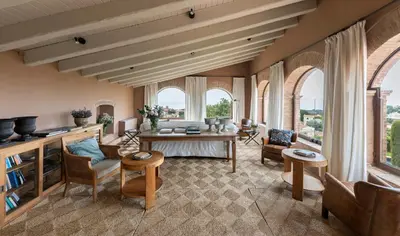a living room with a table and chairs and windows at Can Mora de Dalt in Sant Vicenç de Montalt