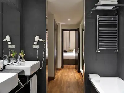 a bathroom with two sinks and a bedroom at H10 Casanova in Barcelona