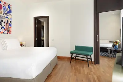 a bedroom with a bed and a green chair at H10 Casanova in Barcelona