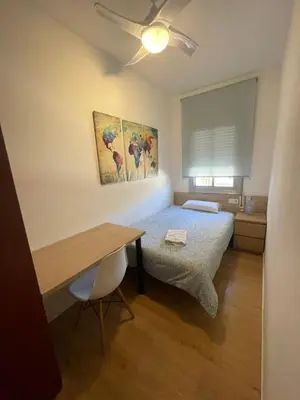 a bedroom with a bed and a desk and a ceiling fan at LG DownTown Sabadell Apartment in Sabadell