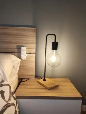 a lamp on a wooden table next to a bed at LG DownTown Sabadell Apartment in Sabadell