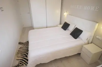 a small bedroom with a white bed with black pillows at Family Deluxe Apartment Beach in Castelldefels