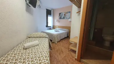 a room with two beds and a table at Hostal Rio De Castro in Barcelona