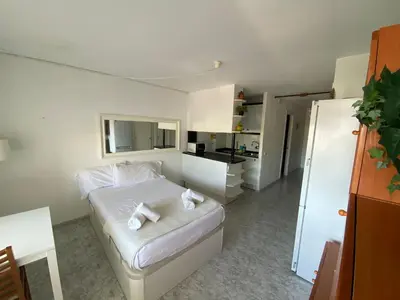 a small bedroom with a bed and a kitchen at The Moon Studio by Hello Homes Sitges in Sitges