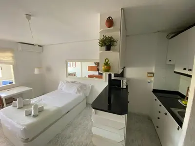 a white bedroom with a bed and a kitchen at The Moon Studio by Hello Homes Sitges in Sitges