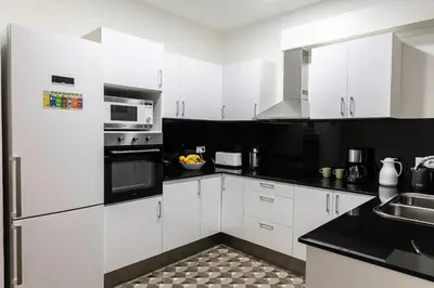 a white kitchen with white cabinets and black appliances at B-Garden BCN in Barcelona