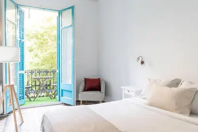 a bedroom with a bed and a window with a chair at B-Garden BCN in Barcelona