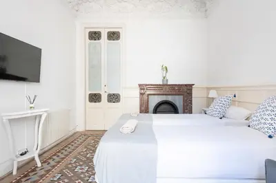 a white bedroom with two beds and a fireplace at B-Garden BCN in Barcelona