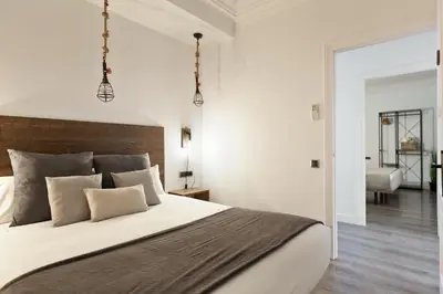 a bedroom with a large bed with white walls at KeyFamily Paradise in Barcelona
