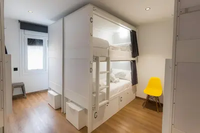 a bedroom with a bunk bed with a yellow chair at Airhostel Barcelona Airport 24h in El Prat de Llobregat
