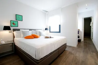 a white bedroom with a large bed with orange pillows at Decô Apartments Barcelona-Diagonal in Barcelona