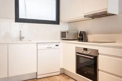 a kitchen with white cabinets and a microwave at Decô Apartments Barcelona-Diagonal in Barcelona