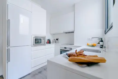 a white kitchen with a counter top with bread on it at Decô Apartments Barcelona-Diagonal in Barcelona