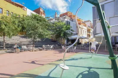 a girl is playing on a swing in a playground at Terrassa de Mar Apartment in Masnou