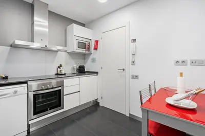 a kitchen with white cabinets and a red table at Sensation Sagrada Familia in Barcelona