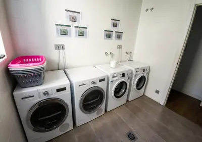 a laundry room with three washing machines and a pink stool at Sensation Sagrada Familia in Barcelona