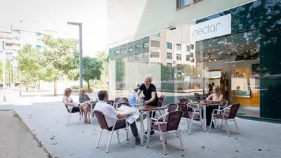 a group of people sitting at tables outside a store at Aura Park Aparthotel Fira Barcelona in Hospitalet de Llobregat