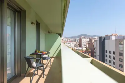 a balcony with two chairs and a table on it at Aura Park Aparthotel Fira Barcelona in Hospitalet de Llobregat