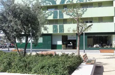 a building with benches and trees in front of it at Aura Park Aparthotel Fira Barcelona in Hospitalet de Llobregat