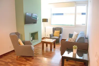 a living room with chairs and a couch and a tv at Sweet BCN Three Bedroom Apartment in Barcelona