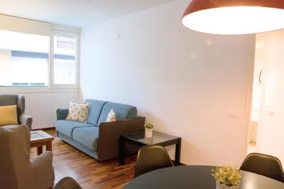 a living room with a blue couch and a table at Sweet BCN Three Bedroom Apartment in Barcelona