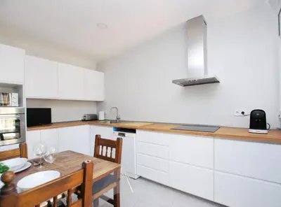 a kitchen with white cabinets and a wooden table at La casa del Pi · La casa del Pi · House in the city, next to Barcelona and beach in Badalona