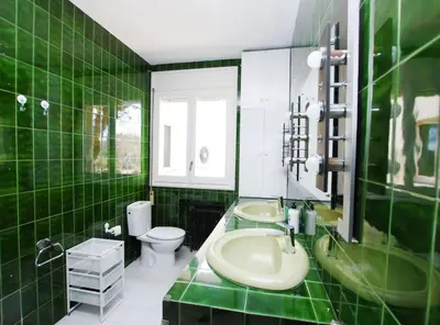 a green tiled bathroom with a sink and a toilet at La casa del Pi · La casa del Pi · House in the city, next to Barcelona and beach in Badalona
