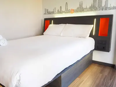a bedroom with a large bed with white sheets at easyHotel Barcelona Fira in Hospitalet de Llobregat