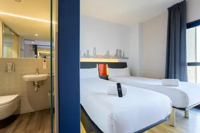 a hotel room with three beds and a sink at easyHotel Barcelona Fira in Hospitalet de Llobregat