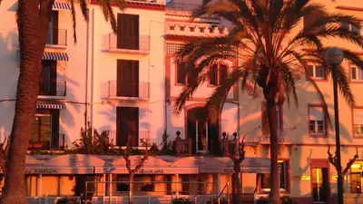 a building with palm trees in front of it at Apartament Mare Nostrum in Sitges