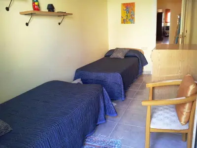 a bedroom with two beds and a chair at Apartament Mare Nostrum in Sitges