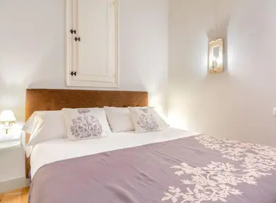 a bedroom with a white bed with two pictures on the wall at BCN Rambla Catalunya Apartments in Barcelona