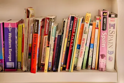a row of books sitting on a shelf at Itaca Hostel in Barcelona