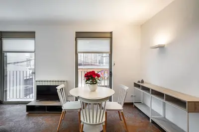 a dining room with a table and chairs with a vase of flowers at Residential Tourist Apartments in Caldes d'Estrac