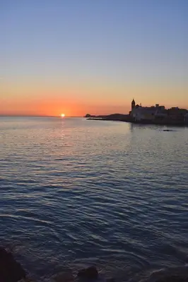 a sunset over a body of water with a small island at Heart of Sitges in Sitges