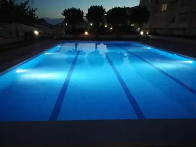 a large blue swimming pool at night at Sitges - Apartamento in Sitges