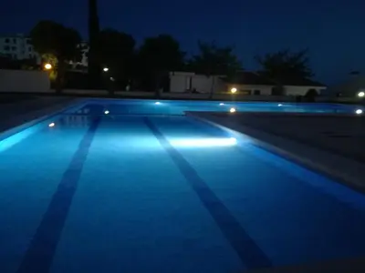 an empty swimming pool at night with blue lights at Sitges - Apartamento in Sitges