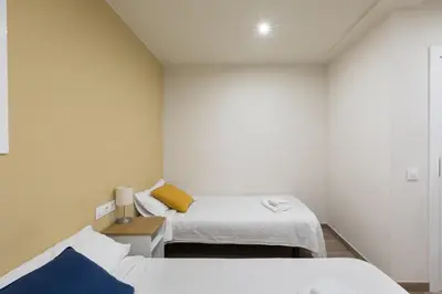a small room with two beds and a nightstand with two beds at Hostal Oliveta in Barcelona