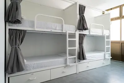 a room with white bunk beds with curtains at Sea Hostel Barcelona in Barcelona